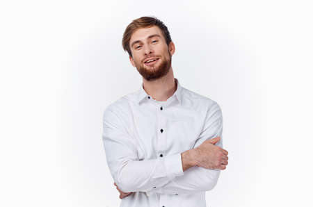 a young man in a white shirt hugs himself with his hands on a light background front viewの写真素材