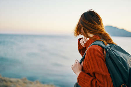 a traveler in the mountains with a backpack on her back goes to the side and the sea is nearbyの写真素材