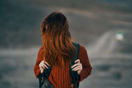 happy traveler in red sweater laughs outdoors near mountains outdoorsの写真素材