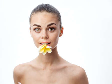 sexy woman with flower in teeth on light background