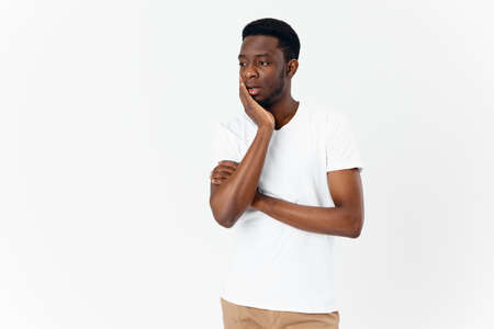 man touching face with hand african appearance model white t-shirt puzzled lookの写真素材
