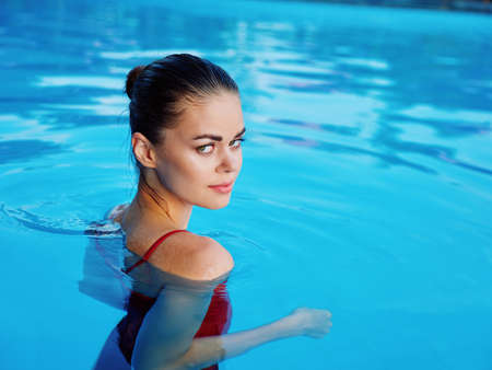 woman in swimsuit in the pool hand near head luxury