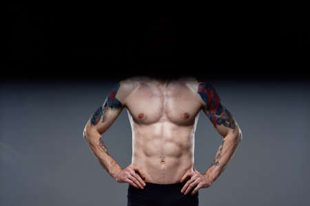 sporty man pumped up press acting out on his arms cropped view gray backgroundの写真素材