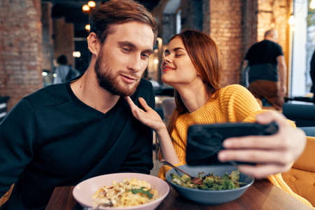 young couple in a restaurant makes a selfie on the phone communicationの写真素材