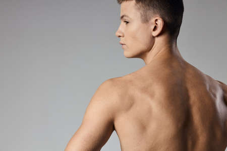 strong athlete with bulging arm muscles naked back back view gray backgroundの写真素材