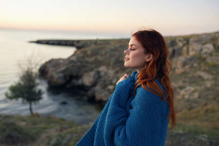 woman in the mountains outdoors with a blue plaid on her shoulders side viewの写真素材