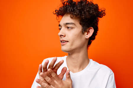 guy in a white t-shirt gesturing with his hand on an orange backgroundの写真素材