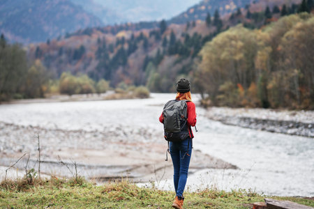 traveler with backpack on nature in autumn forest and transparent river mountains landscapeの写真素材