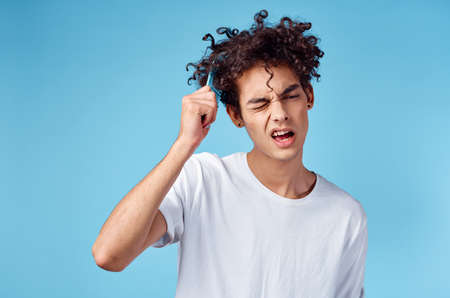 handsome guy with curly hair on a blue background portrait close-up tangled curlsの写真素材