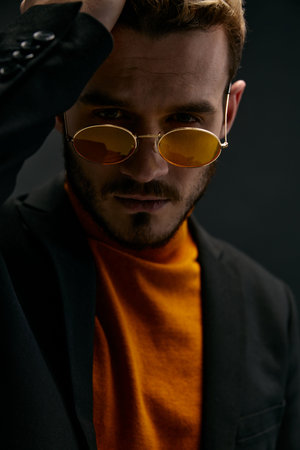 a brutal guy with glasses and a black jacket orange sweater dark backgroundの写真素材