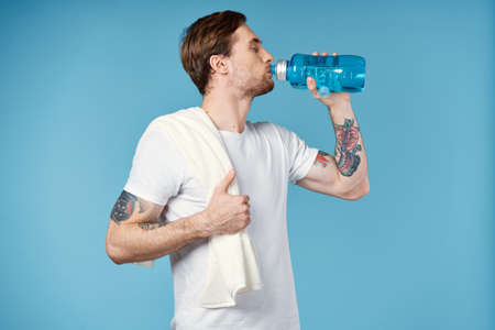 sports man drinking water from a bottle Sport Fitness towel on his shoulderの写真素材