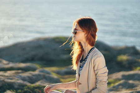 woman in glasses and in a sweater in the mountains near the sea on nature landscapeの写真素材