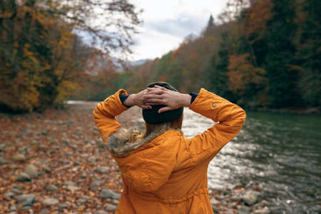 woman hiker admires nature in the mountains autumn riverの写真素材