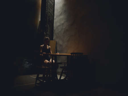 woman in dark room sitting on chair silhouette model naked legs designの写真素材