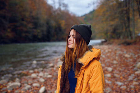 woman in a yellow jacket in the autumn forest fallen leaves riverの写真素材
