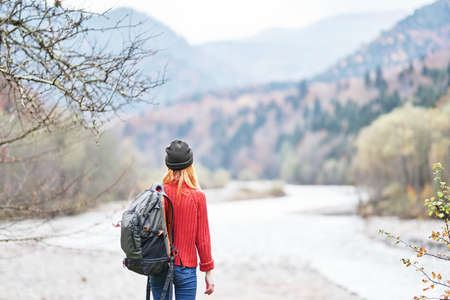 happy woman with backpack rest in the mountains near the river on nature autumn landscape fresh airの写真素材