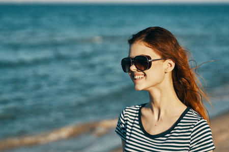 cheerful woman in a t-shirt and glasses are resting on the seashore in the mountainsの写真素材