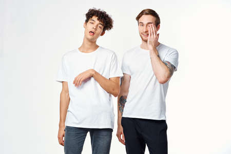 Two cheerful friends in white t-shirts emotions positive light background
