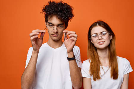 curly guy and a girl in white t-shirts are standing next to each other on an orange backgroundの写真素材