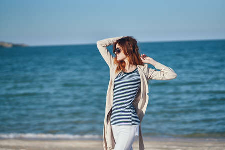 woman gesturing with her hands above her head On the beach near the sea summer skyの写真素材