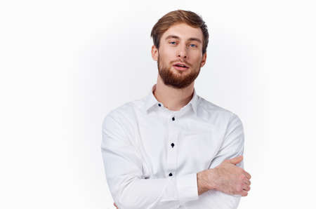 a young man in a white shirt hugs himself with his hands on a light background front viewの写真素材