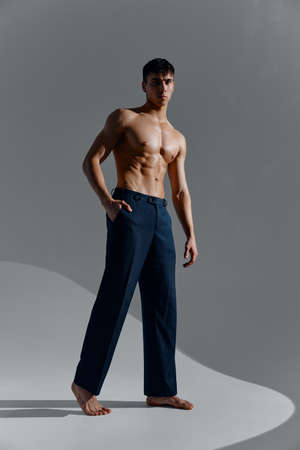 sports guy in jeans and boots on a gray background naked muscles belly torsoの写真素材