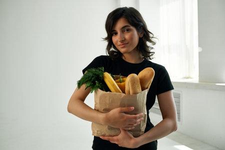 cute brunette at home with a package of groceries healthy food supermarketの写真素材