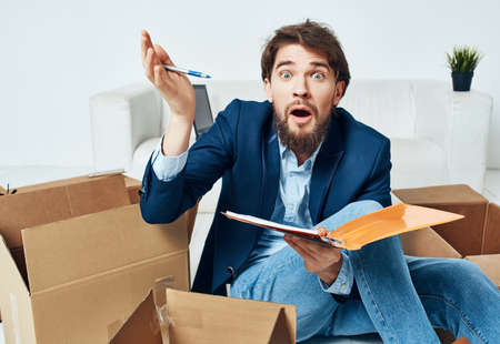 manager with cardboard boxes sitting on the floor moving things officeの写真素材