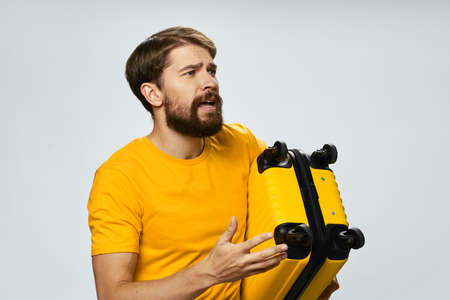 man with yellow suitcase looking to the side on light background cropped viewの写真素材