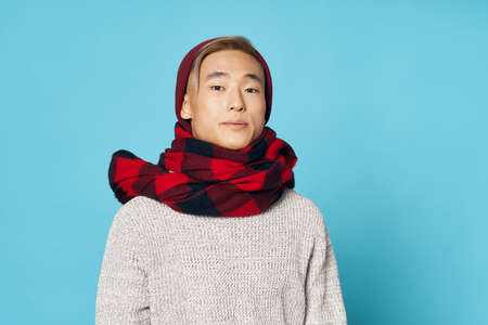 a man in a warm sweater with a scarf around his neck and a hat model of asian appearance