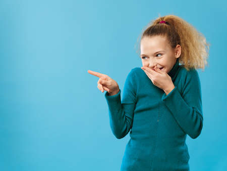 curly girl in green sweater emotions gesture fingers blue backgroundの写真素材