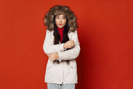 woman of asian appearance in winter jacket red background cool
