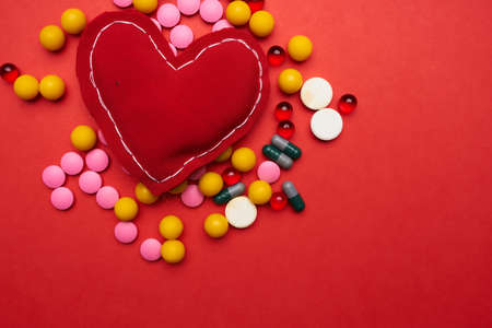 multicolored pills soft heart red background health treatmentの写真素材