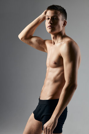 bodybuilder fitness man with a pumped-up torso hand behind head gray background modelの写真素材