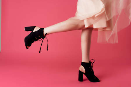 female legs in black shoes posing cropped views pink background fashionの写真素材