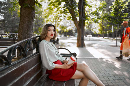 woman in red skirt in the park on the bench outdoorsの写真素材