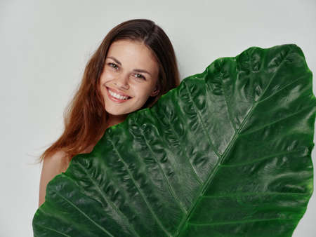 happy woman with green leaf on light background clean skin cosmetology modelの写真素材