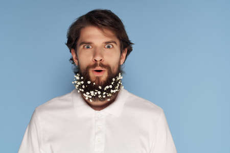 Cheerful man in a white shirt flowers in a beard jewelry fashionの写真素材