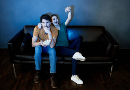 married couple at home watching tv on the couch popcorn