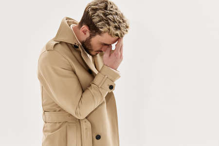 man holds his hand near his face fashionable hairstyle coat lifestyleの写真素材