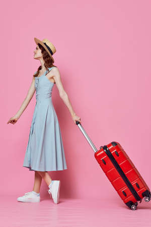 woman tourist in hat with red suitcase passenger lifestyle pink backgroundの写真素材