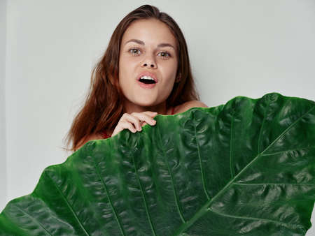 pretty red-haired woman green leaf bare shoulders close-up