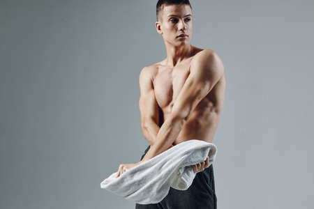 sporty man with towel in hand posing muscles isolated backgroundの写真素材