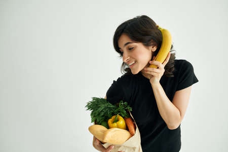 cheerful woman in black t-shirt with a package of supermarket groceriesの写真素材
