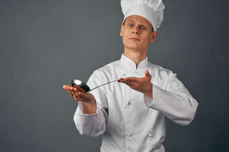 a cook with a ladle in his hands is trying a restaurant dish professional kitchenの写真素材