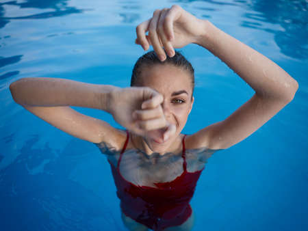 cheerful woman in a red swimsuit in the pool gesturing with her handsの写真素材