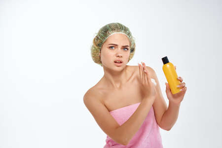 woman with unhappy facial expression in pink towel lotion skin care
