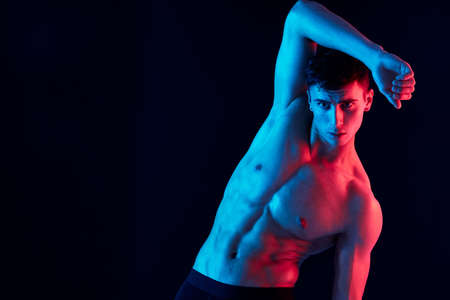 man holding hand near face on dark background and inflated torso bodybuilderの写真素材