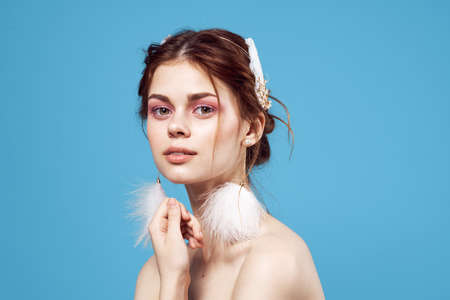 woman with fluffy earrings nude shoulders Glamor blue background