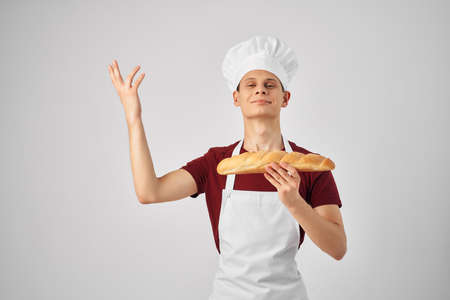 a man chef in a white apron holds a loaf in his hands Bakerの写真素材